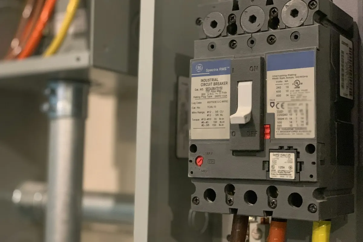 Tampak dekat molded-case circuit breaker di dalam panel listrik industri