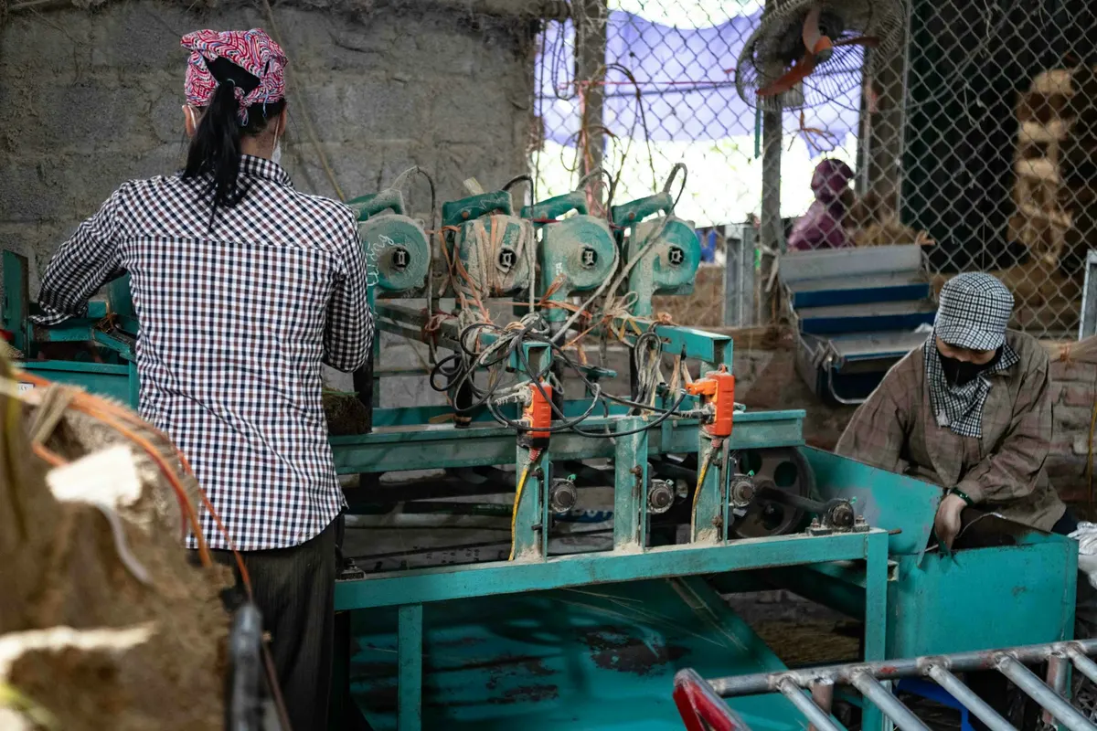 Pekerja di mesin bercat hijau pada lini produksi bengkel yang sibuk