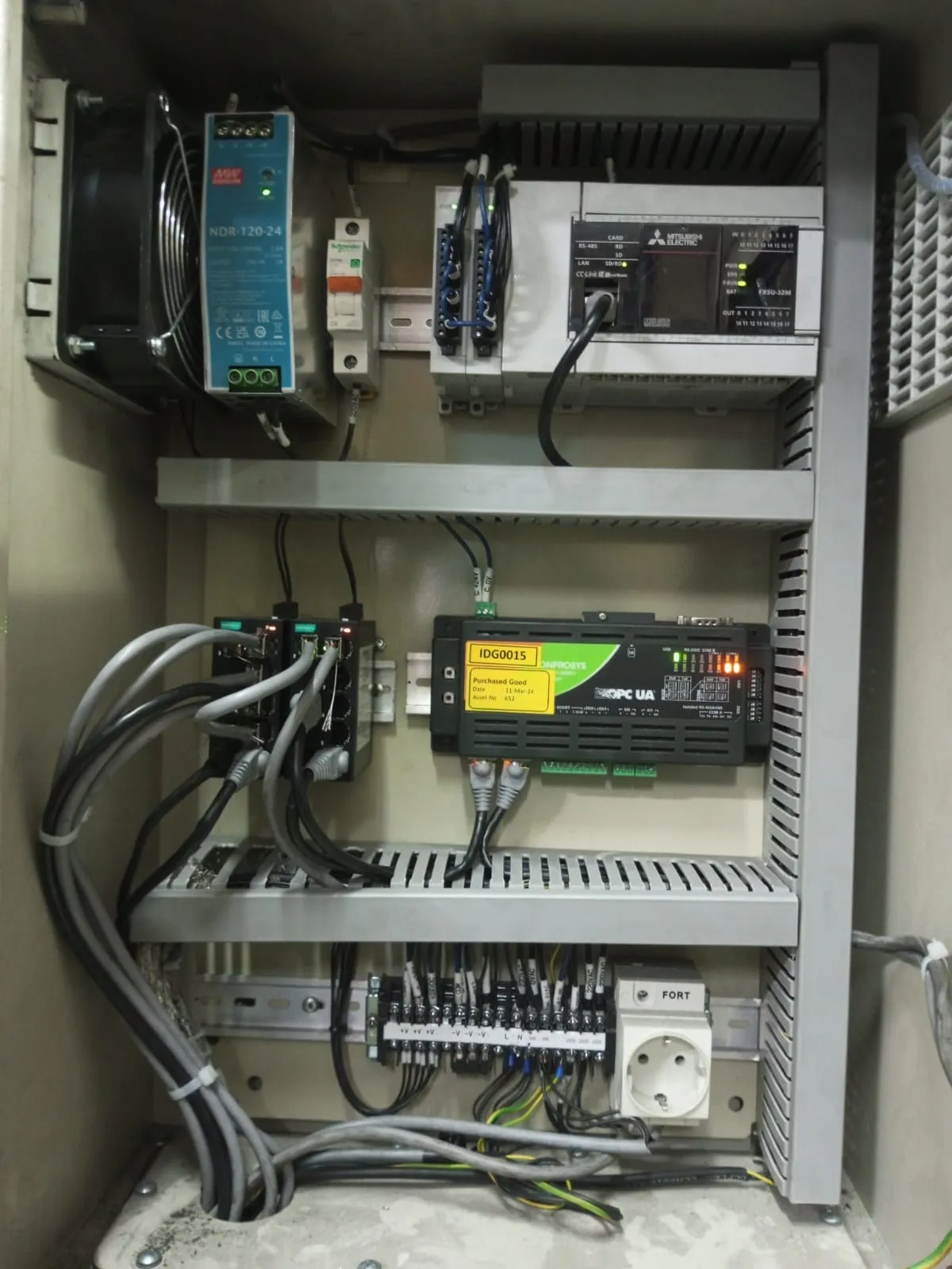 Panel akuisisi data yang tertata: PLC, gateway OPC UA, switch jaringan, dan terminal berlabel