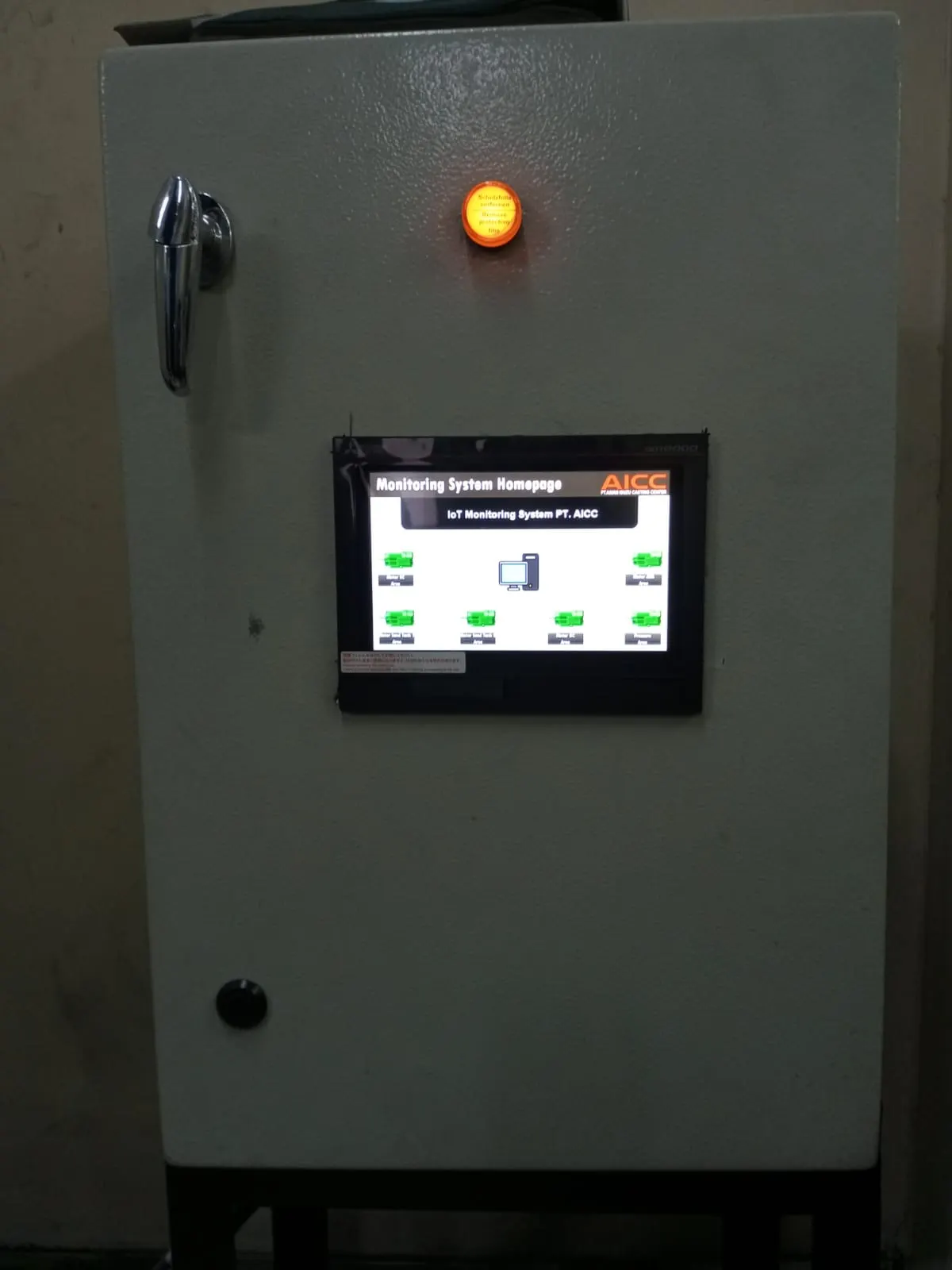 Panel monitoring dengan layar sentuh HMI dan lampu status di area utilitas