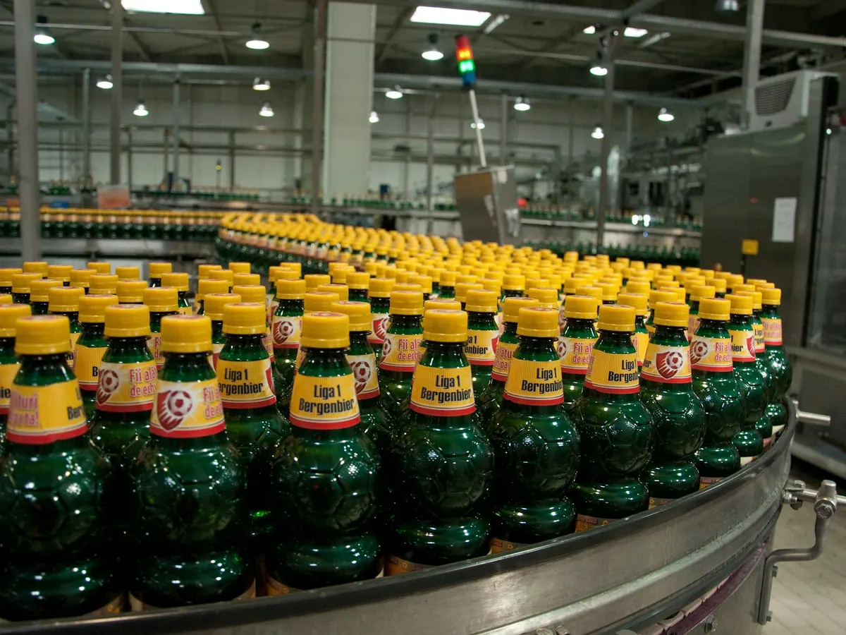 Botol minuman berjalan di conveyor lini pengisian pabrik